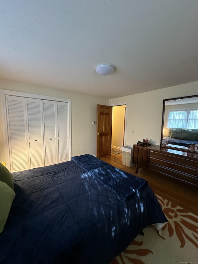 bedroom with dark wood-type flooring and a closet