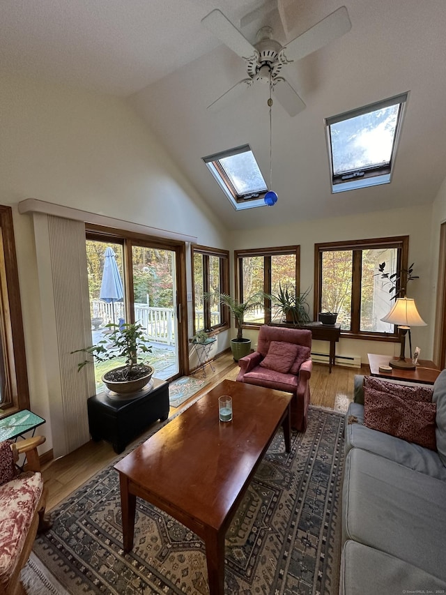 sunroom featuring a baseboard radiator, lofted ceiling with skylight, and ceiling fan