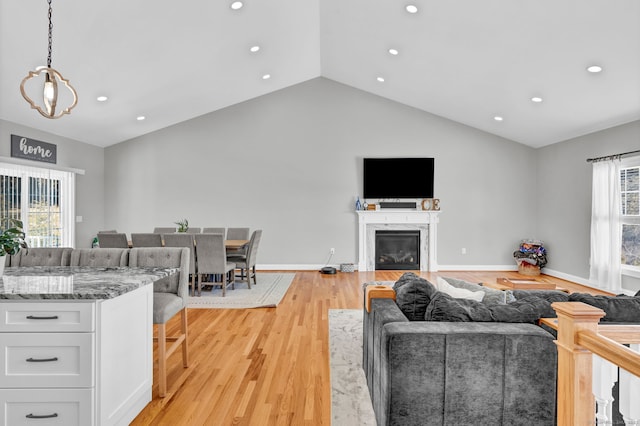 living room featuring an inviting chandelier, light hardwood / wood-style floors, and vaulted ceiling