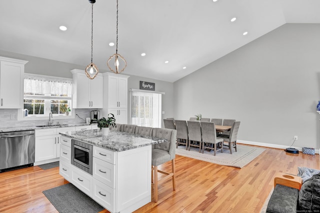 kitchen featuring decorative light fixtures, sink, white cabinets, a center island, and stainless steel appliances