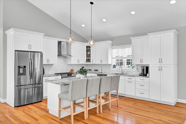 kitchen featuring wall chimney exhaust hood, white cabinetry, appliances with stainless steel finishes, and a kitchen island