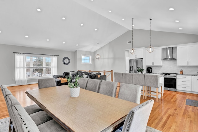 dining room with lofted ceiling, a notable chandelier, and light hardwood / wood-style floors