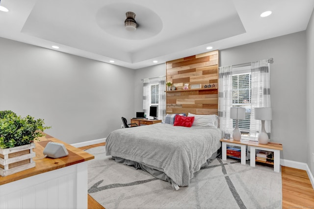 bedroom with multiple windows, a tray ceiling, and ceiling fan