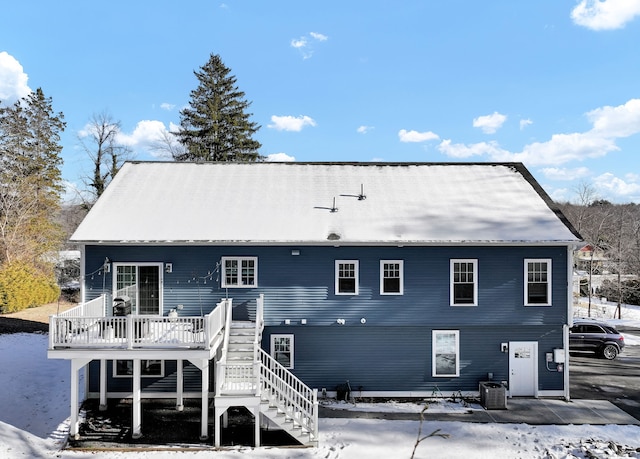 snow covered house featuring a wooden deck and central AC