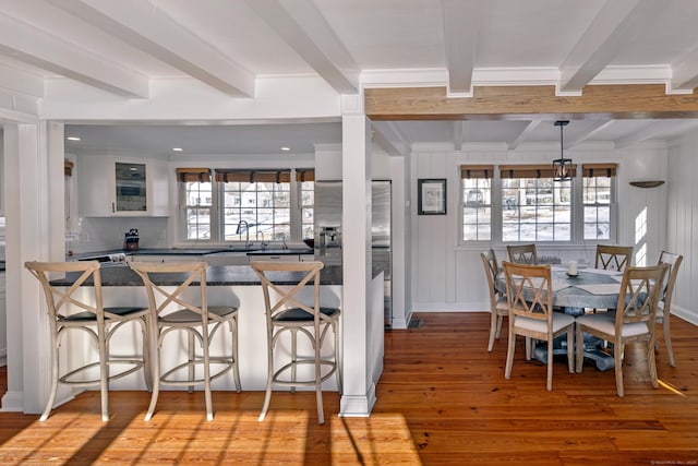 kitchen featuring beamed ceiling, white cabinetry, a kitchen breakfast bar, and light hardwood / wood-style flooring