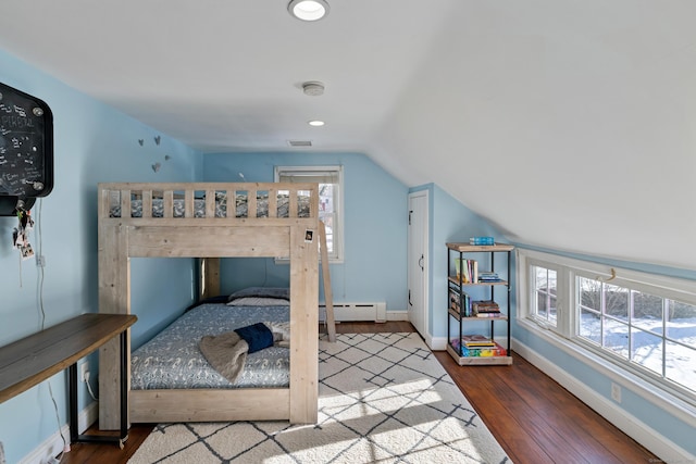 bedroom featuring multiple windows, wood-type flooring, lofted ceiling, and a baseboard heating unit