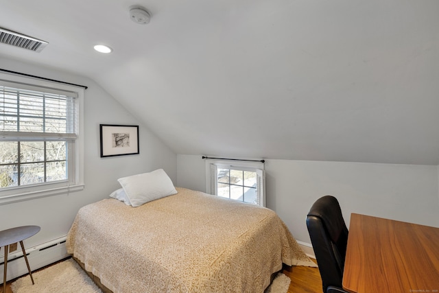 bedroom featuring vaulted ceiling, a baseboard heating unit, and light hardwood / wood-style floors