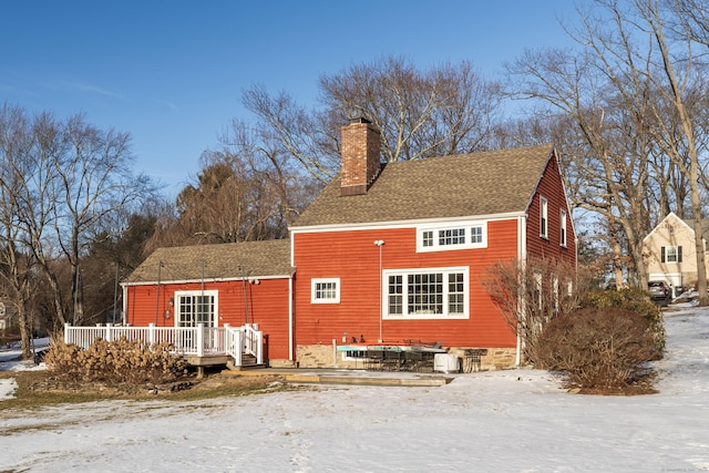 snow covered rear of property featuring a deck