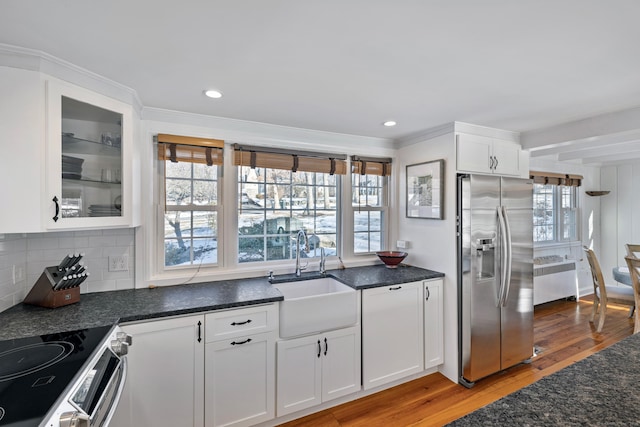 kitchen featuring appliances with stainless steel finishes, tasteful backsplash, white cabinetry, sink, and light hardwood / wood-style flooring