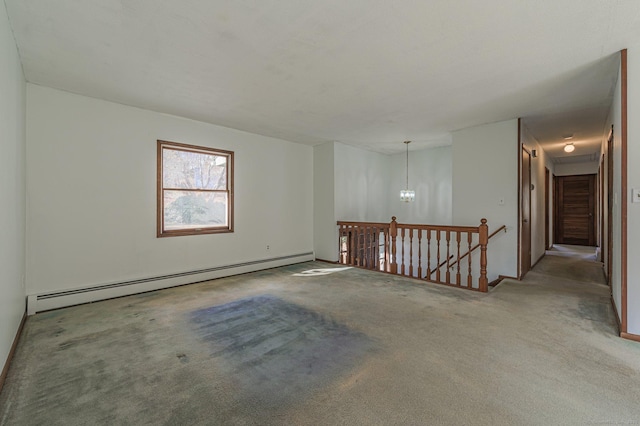 spare room featuring a baseboard heating unit, a chandelier, and carpet