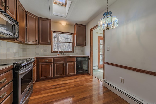 kitchen featuring pendant lighting, sink, a baseboard heating unit, stainless steel appliances, and dark hardwood / wood-style flooring