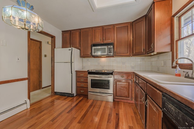 kitchen featuring sink, backsplash, hanging light fixtures, stainless steel appliances, and a baseboard radiator