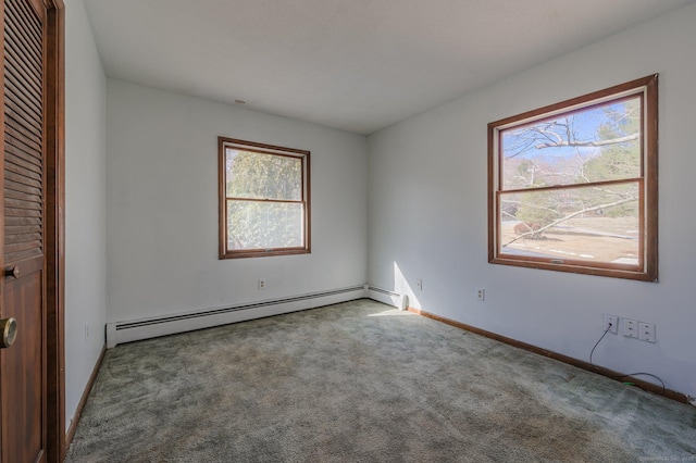 carpeted spare room featuring a baseboard heating unit and a wealth of natural light