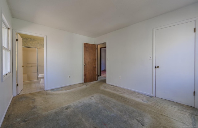 unfurnished bedroom featuring light colored carpet and connected bathroom