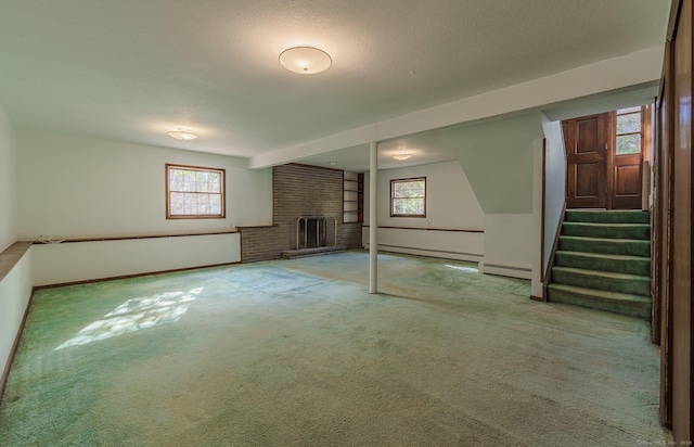 basement featuring a fireplace, carpet floors, a textured ceiling, and a baseboard heating unit