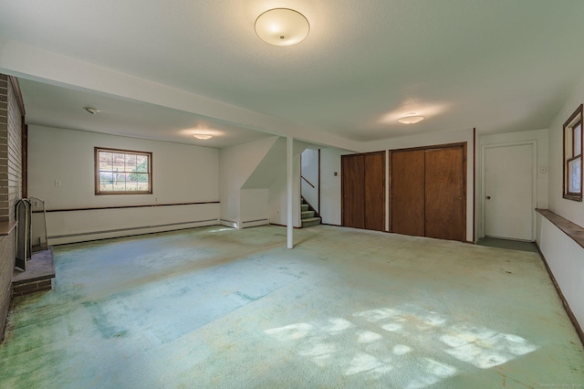 basement featuring a baseboard heating unit and light colored carpet