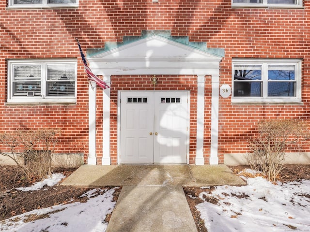 snow covered property entrance featuring a garage