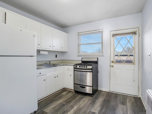 kitchen with sink, dark wood-type flooring, stainless steel gas range, white refrigerator, and white cabinets