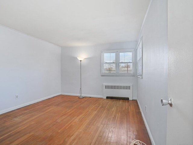 empty room featuring wood-type flooring and radiator heating unit