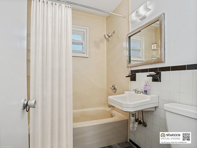 bathroom featuring tile walls, shower / bath combination with curtain, and toilet