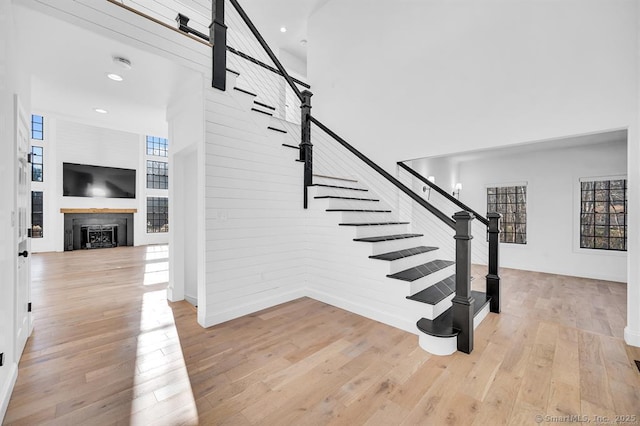 staircase with wood-type flooring and a high ceiling