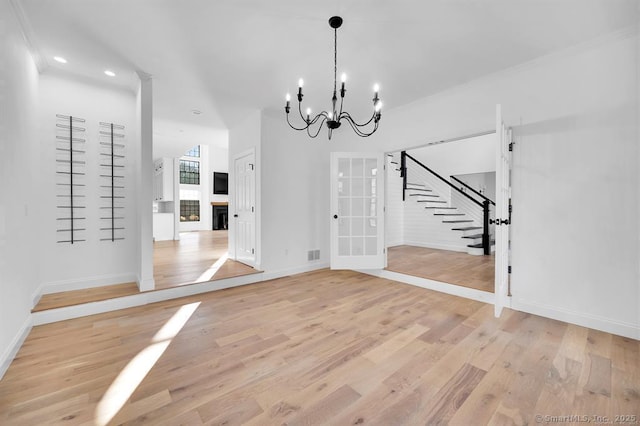 unfurnished dining area featuring an inviting chandelier, ornamental molding, and light hardwood / wood-style flooring