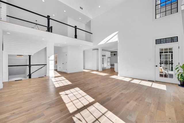 unfurnished living room with light hardwood / wood-style floors and a high ceiling