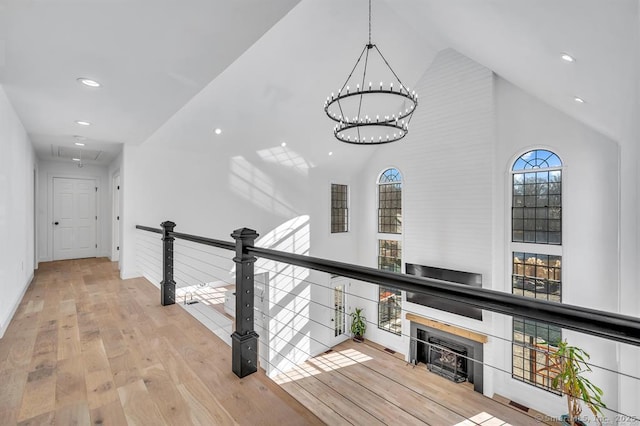 corridor featuring a notable chandelier, high vaulted ceiling, and light hardwood / wood-style floors