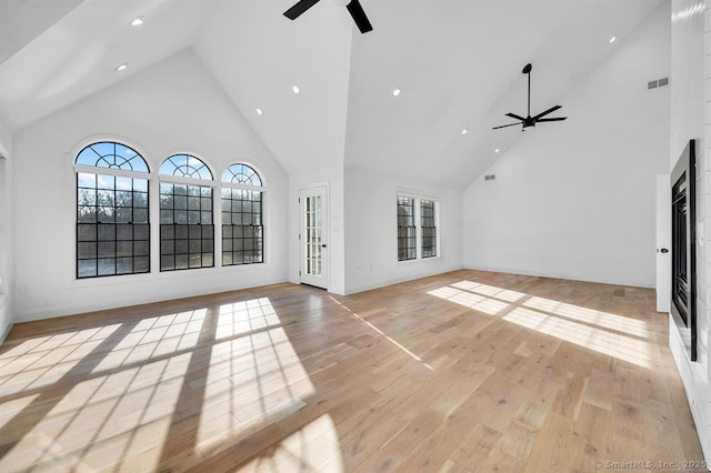 unfurnished living room with light hardwood / wood-style floors, ceiling fan, and a high ceiling