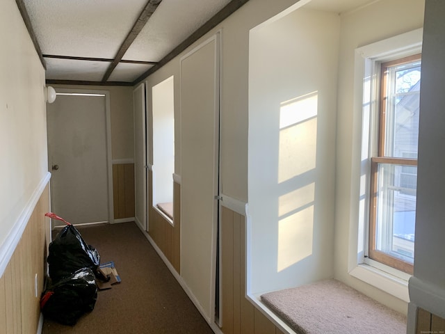 hallway with a textured ceiling and dark colored carpet