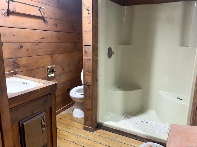 bathroom with wooden walls, vanity, wood-type flooring, toilet, and walk in shower