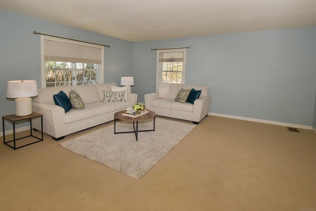 living area with light carpet, visible vents, and baseboards