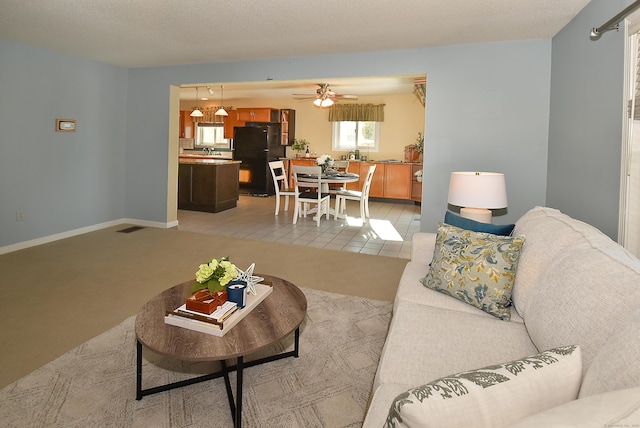 living area featuring baseboards, ceiling fan, visible vents, and light colored carpet