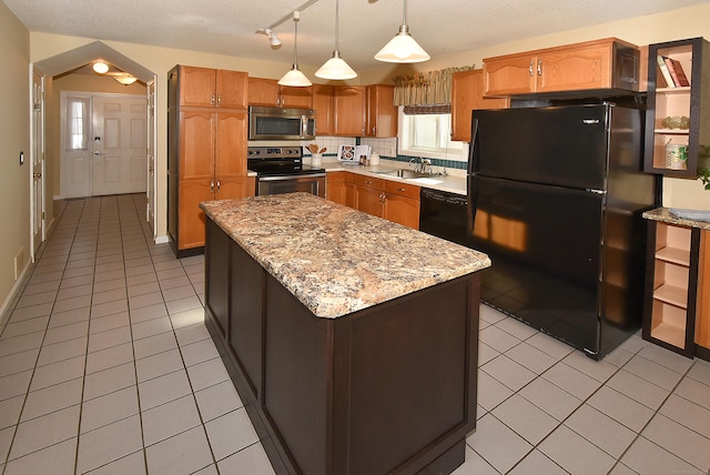 kitchen with pendant lighting, light tile patterned floors, a kitchen island, a sink, and black appliances