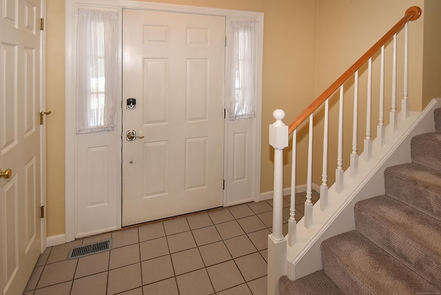 entrance foyer featuring light tile patterned floors, stairs, visible vents, and baseboards