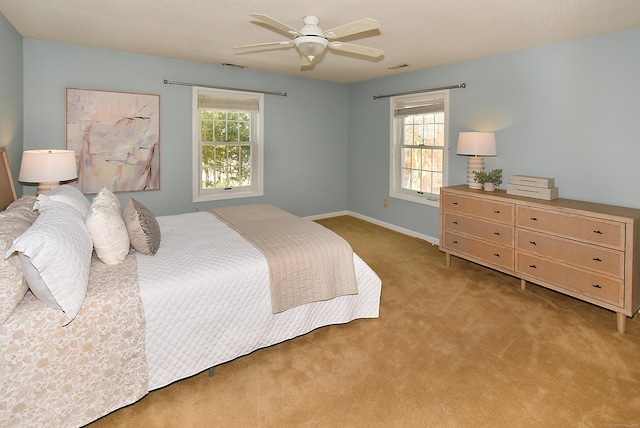 bedroom featuring baseboards, visible vents, ceiling fan, and light colored carpet