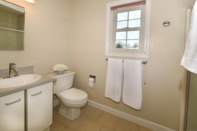 bathroom with toilet, vanity, baseboards, and tile patterned floors