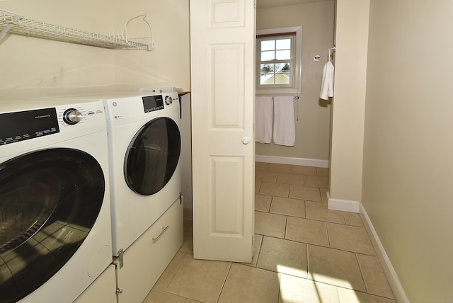 washroom with laundry area, baseboards, washing machine and clothes dryer, and light tile patterned floors