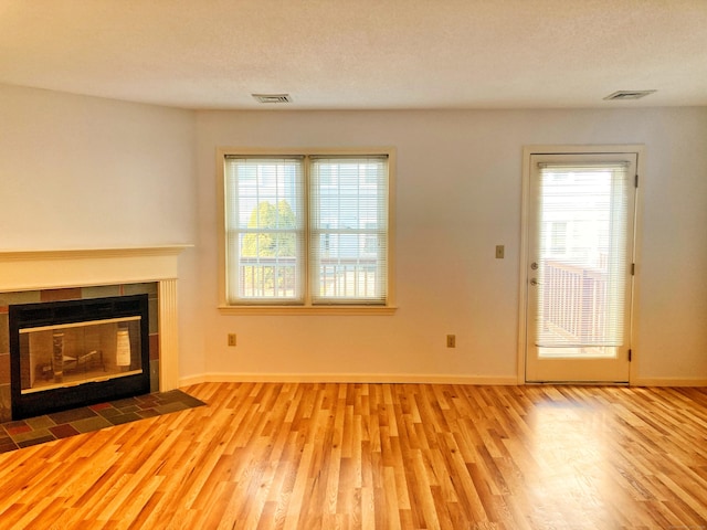 unfurnished living room featuring a fireplace, light hardwood / wood-style flooring, and a textured ceiling