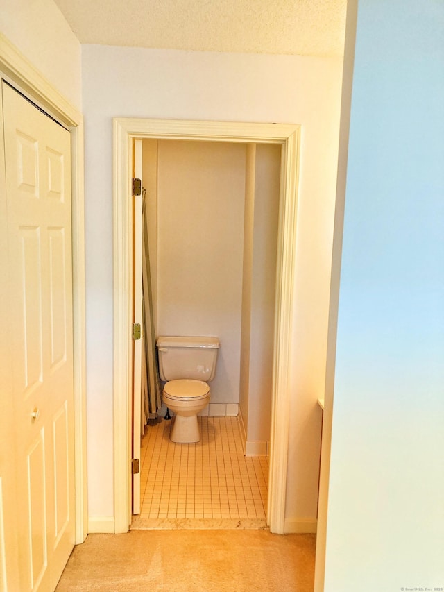 hall featuring light colored carpet and a textured ceiling