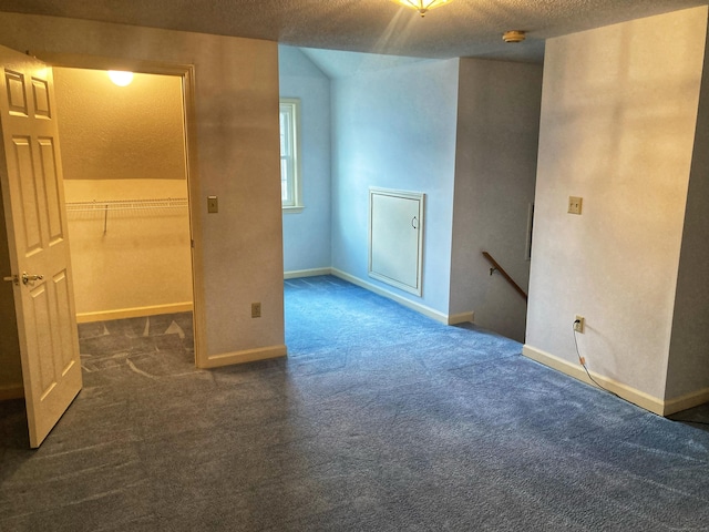 spare room featuring dark carpet and a textured ceiling