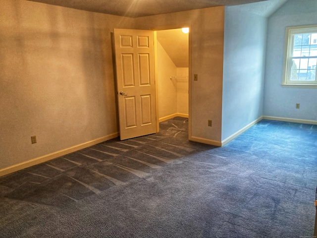 carpeted spare room with vaulted ceiling