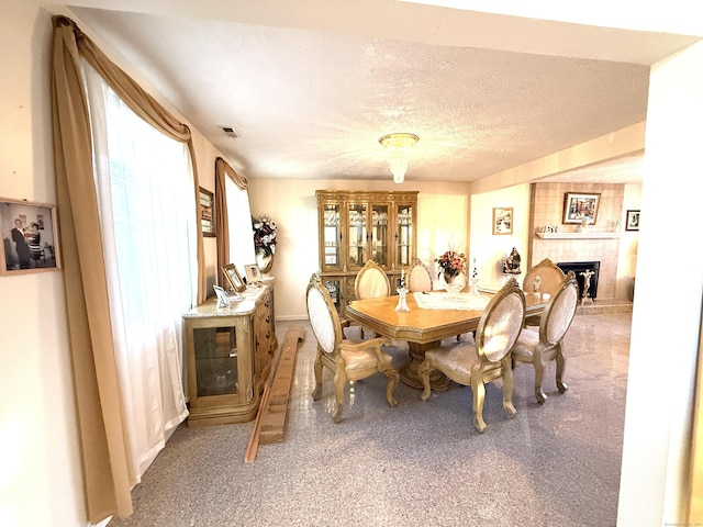 dining room featuring a tile fireplace, carpet, and a textured ceiling