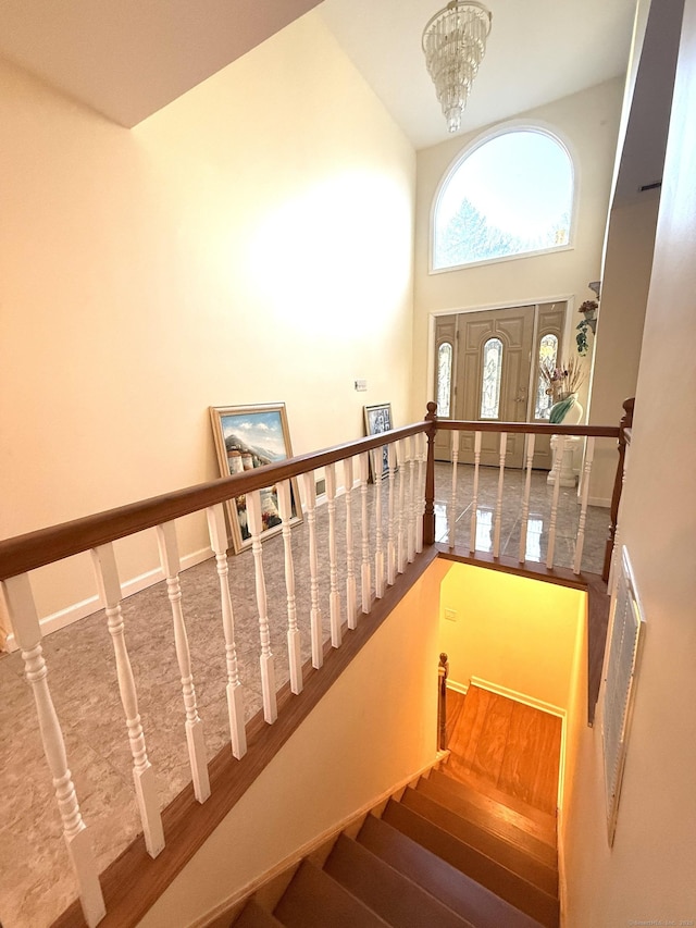 staircase with a towering ceiling and an inviting chandelier