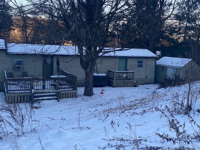 snow covered rear of property with a storage unit and a deck