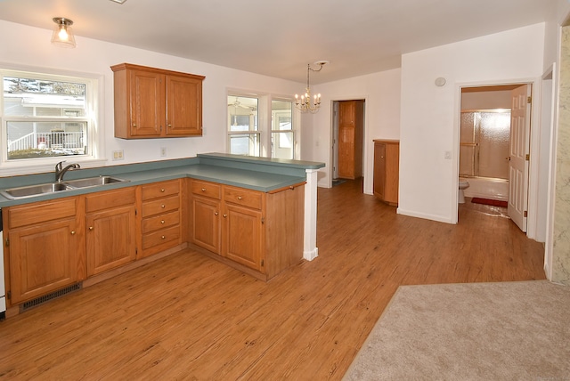 kitchen with a chandelier, sink, pendant lighting, and light wood-type flooring