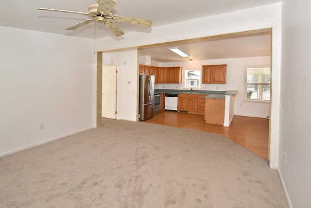 kitchen featuring sink, ceiling fan, stainless steel appliances, dark carpet, and kitchen peninsula