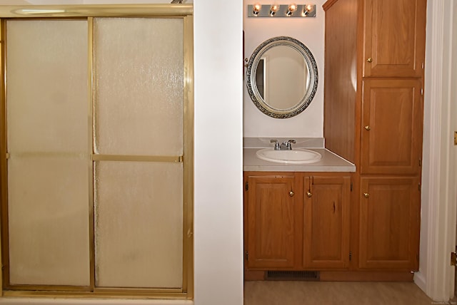 bathroom with a shower with door and vanity