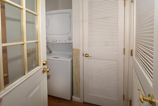 washroom with dark wood-type flooring and stacked washer / dryer