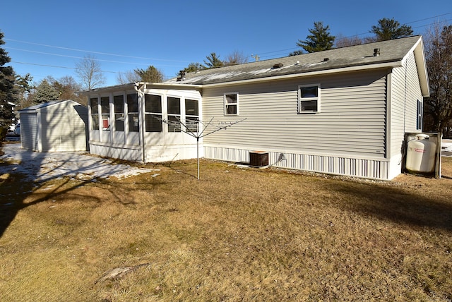 rear view of house featuring a sunroom and a lawn